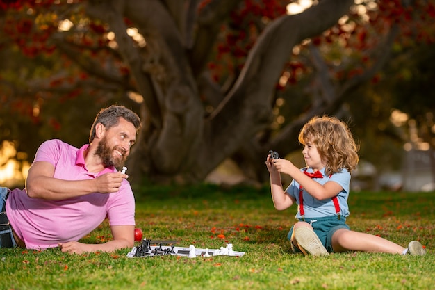 Glücklicher Vater und Sohn, die Schach spielen, die auf Gras am Vatertag des Rasenparks und Elternschaftskonzept liegen