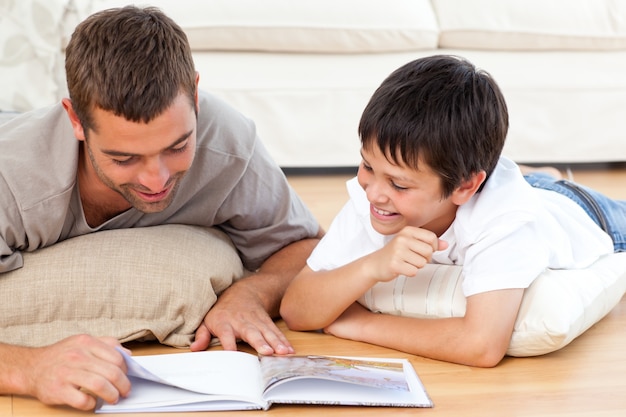 Glücklicher Vater und Sohn, die zusammen ein Buch auf dem Boden liest