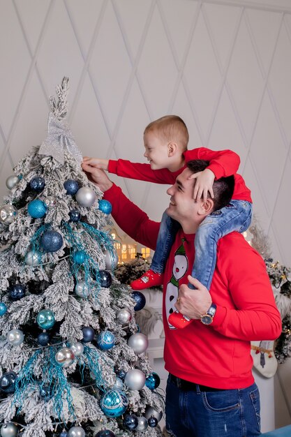 Glücklicher Vater und Sohn genießen es, den Weihnachtsbaum mit Weihnachtskugeln zu schmücken