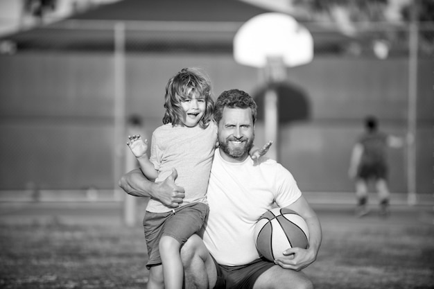 Glücklicher Vater und Sohn spielen Basketball mit Familie im Freien