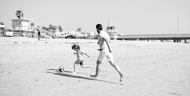 Glücklicher vater und sohn spielen fußball und haben spaß am sommersandstrand familienurlaub elternschaft