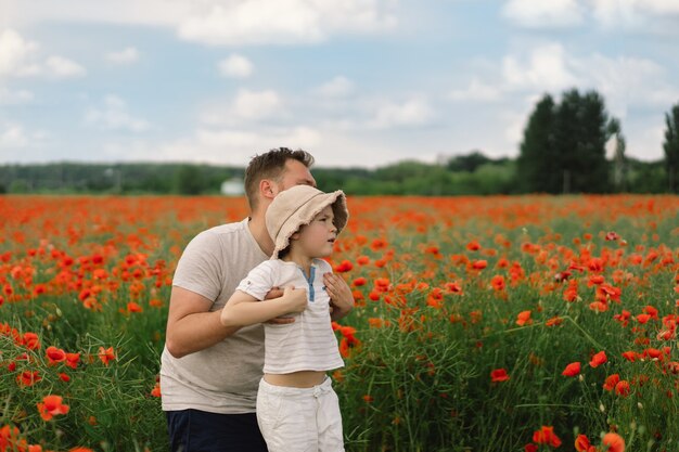 Glücklicher Vatertag kleiner Junge und Vater spielen in einem schönen Feld mit roten Mohnblumen