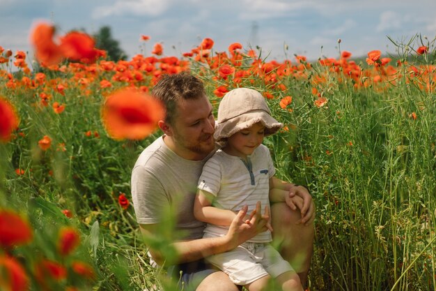 Glücklicher Vatertag kleiner Junge und Vater spielen in einem schönen Feld mit roten Mohnblumen