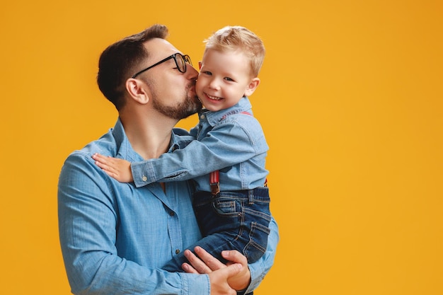 Glücklicher Vatertag, süßer Vater und Sohn, die sich auf gelbem Hintergrund umarmen