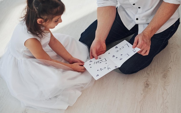 Glücklicher Vatertag Tochter überrascht Papa, indem sie Postkarte mit Herz gibt