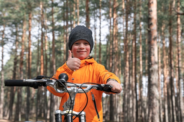 Glücklicher Vorschüler fährt mit dem Fahrrad durch den Park auf einem Radweg