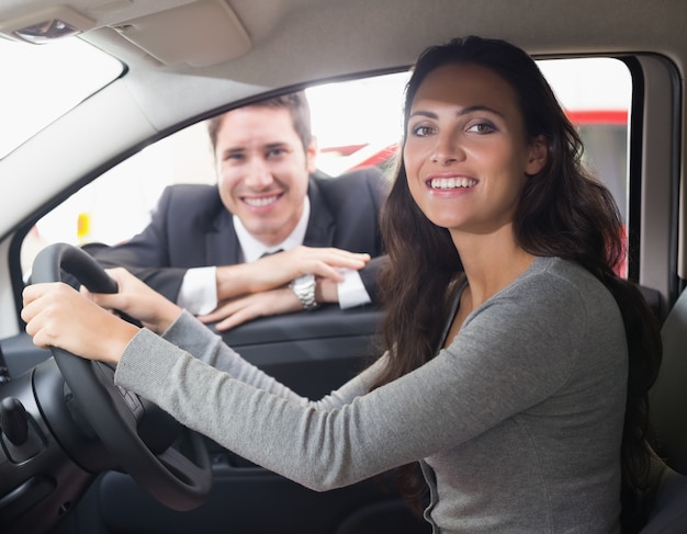 Glücklicher weiblicher Fahrer am Steuer, der in ihrem Auto sitzt