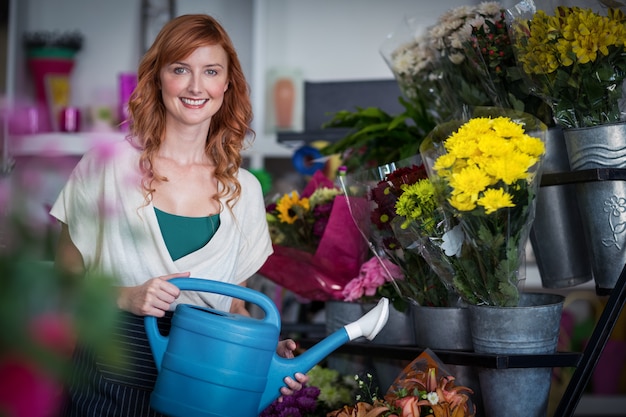 Glücklicher weiblicher Florist, der Blumen wässert