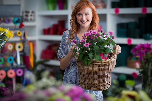 Glücklicher weiblicher Florist, der Blumenkorb hält