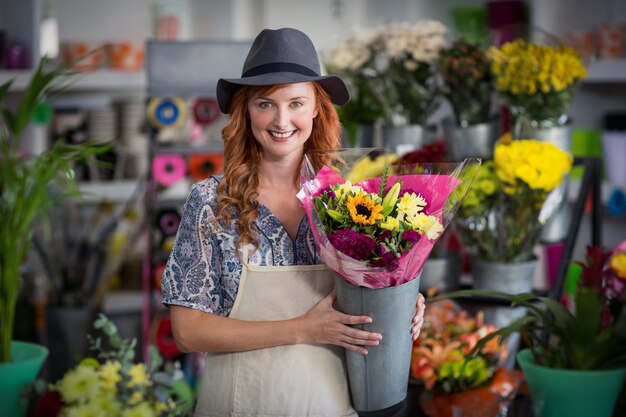 Glücklicher weiblicher Florist, der Blumenvase hält