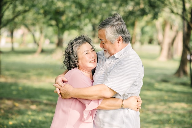 Glückliches älteres asiatisches Paar, das eine gute Zeit hat, die im Freien im Park umarmt und umarmt