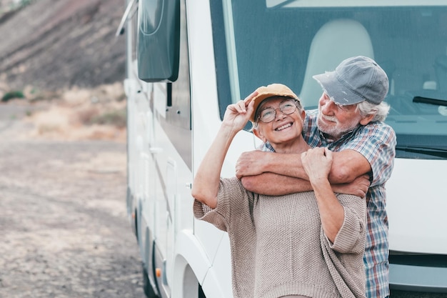 Glückliches älteres Paar auf Urlaubsreise, das vor dem Wohnmobil steht und das Reiseziel genießt