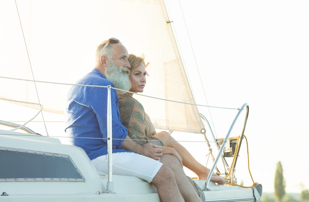 Glückliches älteres Paar, das auf der Seite des Segelboots oder des Yachtdecks steht, das auf See schwimmt.