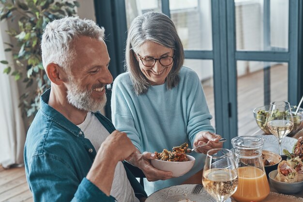 Glückliches älteres Paar, das beim gemeinsamen Abendessen kommuniziert und lächelt