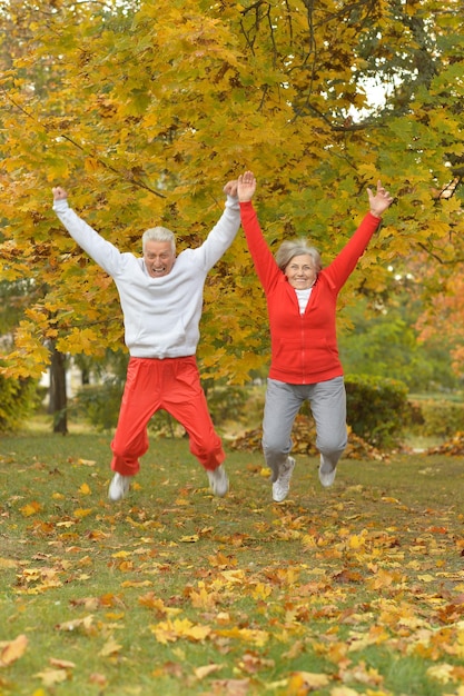 Glückliches älteres Paar, das im Herbstpark springt