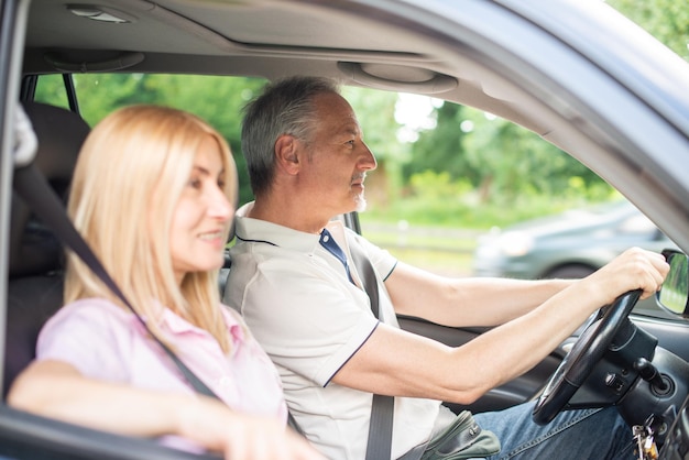 Glückliches älteres Paar, das in ihrem Auto unterwegs ist