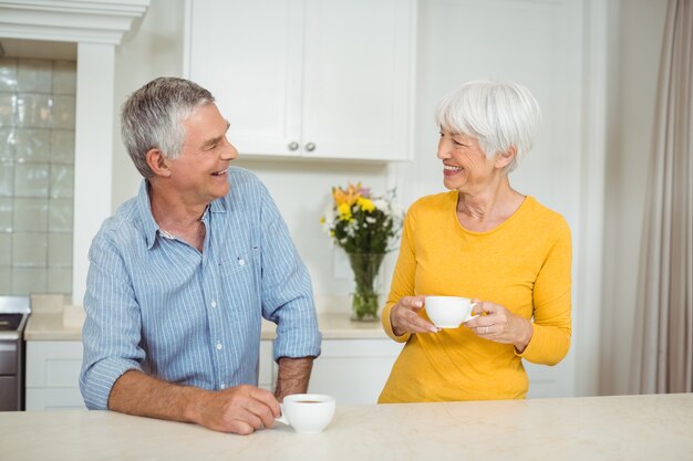 Glückliches älteres Paar, das Kaffee in der Küche trinkt