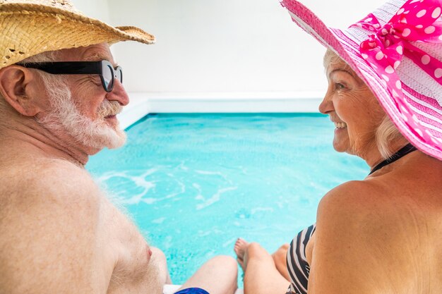 Glückliches älteres Paar, das Party im Swimmingpool hat