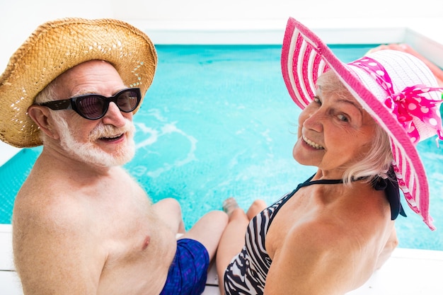 Glückliches älteres Paar, das Party im Swimmingpool hat