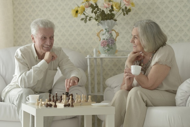 Glückliches älteres Paar, das sich zu Hause ausruht und Schach spielt