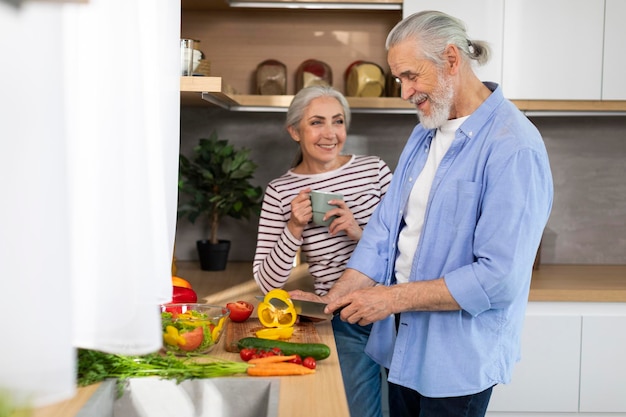 Glückliches älteres Paar, das sich zu Hause entspannt, gesundes Essen kocht und Tee trinkt