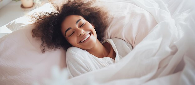 Glückliches afrikanisches Mädchen auf einem Bett mit Kopierraum, lacht und spielt mit einer Decke, während es in die Kamera schaut