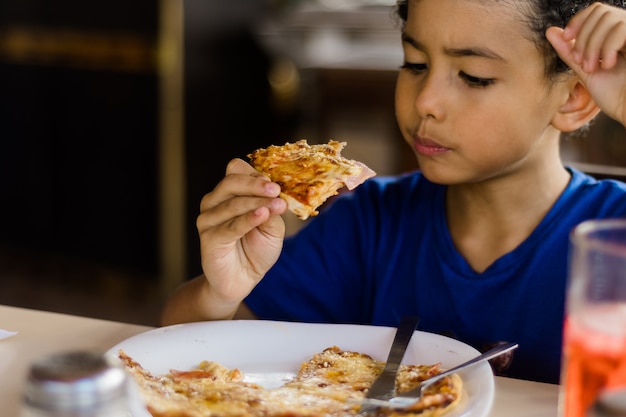 Glückliches afroamerikanisches Kind, das Pizza isst.