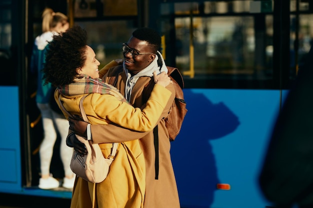 Glückliches afroamerikanisches Paar, das sich am Busbahnhof trifft