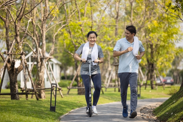 Glückliches asiatisches älteres Paar, das draußen im Park joggt.