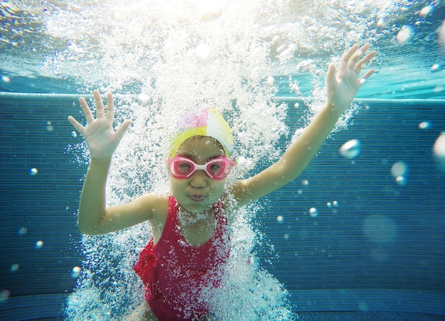 glückliches asiatisches Kind, das unter Wasser im Sommer schwimmt