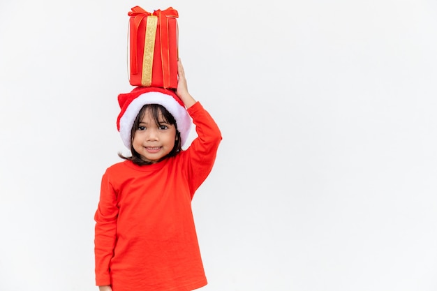 Glückliches asiatisches Kind in Santa Red Hat mit Weihnachtsgeschenken. Weihnachtszeit auf weißem Hintergrund.