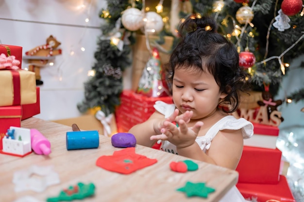 Glückliches asiatisches kleines Mädchen hat Spaß am Weihnachtstag. Kind mit Elternteil mit Weihnachtsbaumdekoration zu Hause im Urlaub.