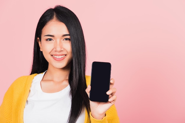 Glückliches asiatisches Porträt, schöne, süße junge Frau, jugendlich, lächelnd, aufgeregt, Handy-Studioaufnahme mit leerem Bildschirm, isoliert auf rosa Hintergrund, thailändische weibliche Show, Smartphone, leerer Bildschirmbereich