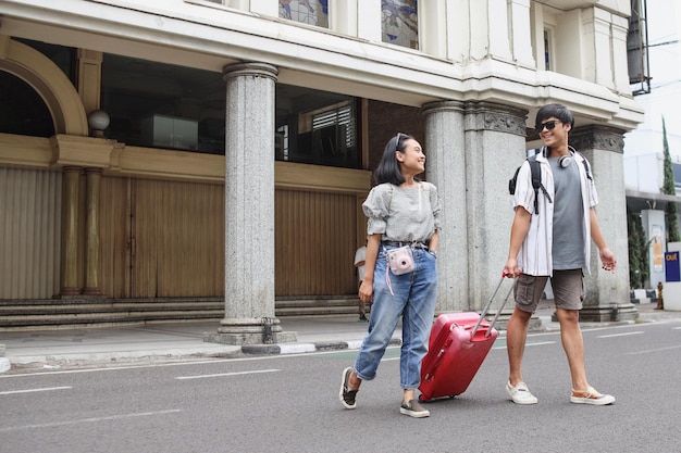 Glückliches asiatisches Touristenpaar, das gemeinsam auf der Straße spaziert Reiseurlaub und Beziehungskonzept