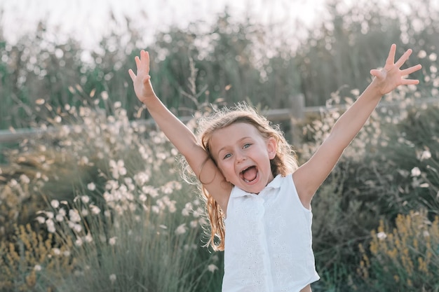 Glückliches aufgeregtes emotionales Kindermädchen auf Sommernaturhintergrund Glückliches Gesicht