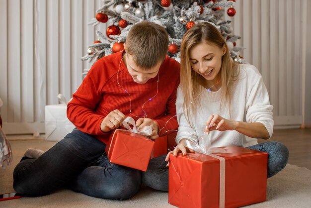 Glückliches aufgeregtes Familienpaar packt Weihnachtsgeschenkbox am Feiertagsmorgen in schönem Zimmer aus