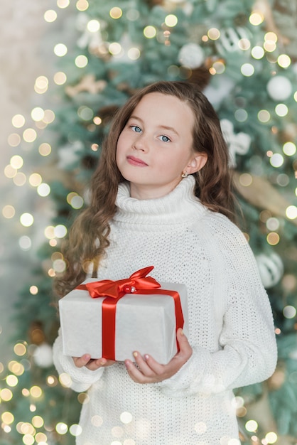 Glückliches aufgeregtes Mädchenkind, das Weihnachtsgeschenkbox hält.