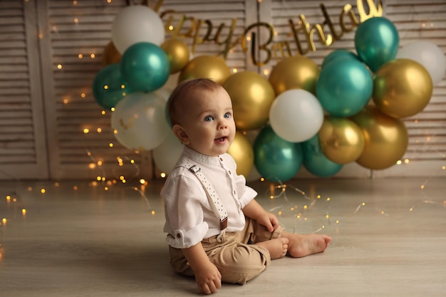 Glückliches Baby auf dem Hintergrund von Ballons mit Girlanden und der Aufschrift alles Gute zum Geburtstag