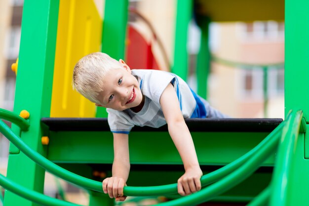 Glückliches Baby, das auf dem Spielplatz im Hof im Sommer spielt