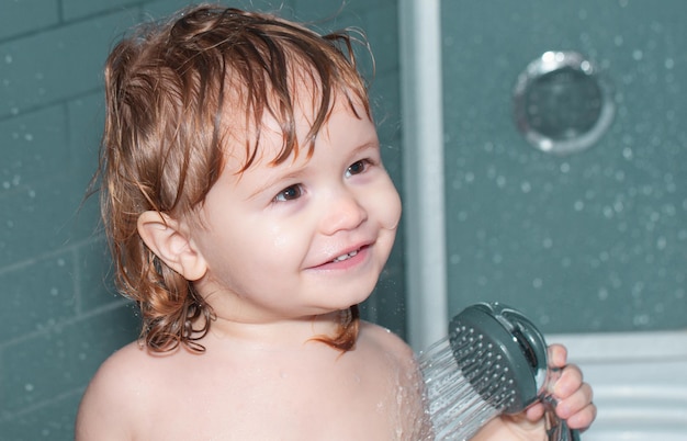 Foto glückliches baby, das ein bad nimmt, das mit schaumblasen spielt, kind, das unter einer dusche badet, säuglingswäsche und b