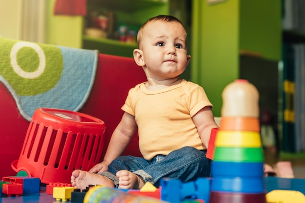 Glückliches Baby, das im Kindergarten mit Bauklötzen spielt.