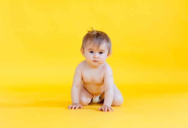 Glückliches Baby, das isoliert auf einem gelben Hintergrund kriecht. Baby in Windel kriecht