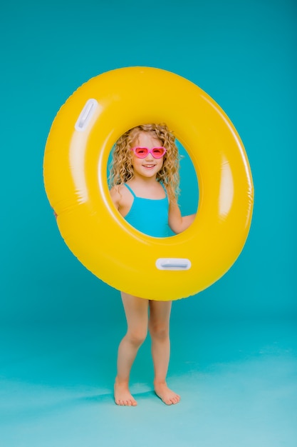 Glückliches Baby im Badeanzug mit dem Kreis lokalisiert auf blauem Hintergrund