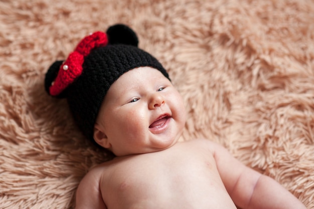 Glückliches Baby in der Mütze liegt