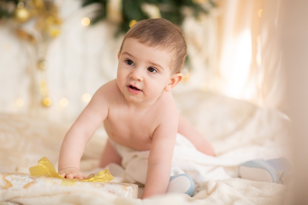 Glückliches Baby in einer Weihnachtsmütze mit einem Geschenk