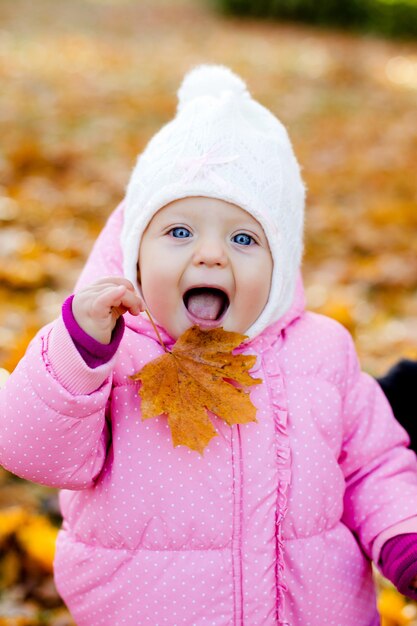 Glückliches Baby mit Herbstblatt im weißen Hut