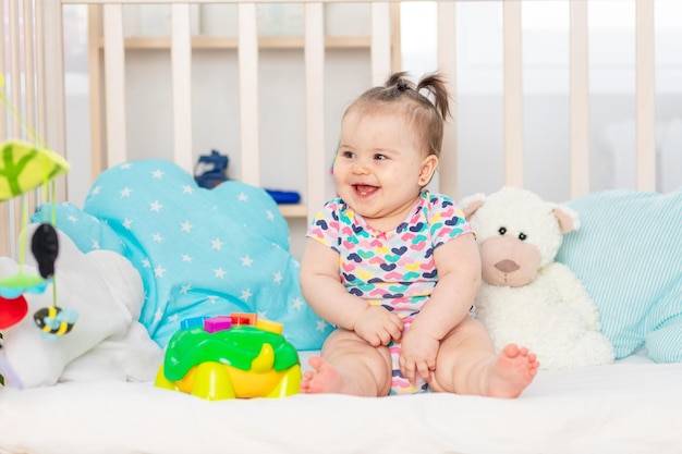 Glückliches Baby mit Spielzeug in der Krippe zu Hause Spielzeug für Kleinkinder Frühe Entwicklung