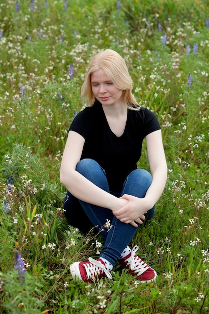 Glückliches blondes Mädchen umgeben durch Blumen