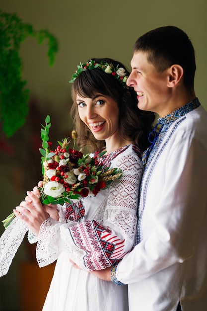 Glückliches Brautpaar in bestickter ethnischer Kleidung in den Armen des anderen