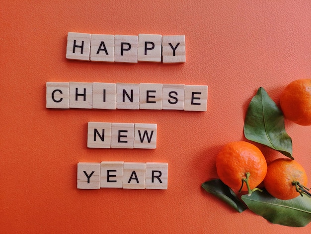 Foto glückliches chinesisches neujahr auf einer orangefarbenen wand mit drei mandarinen